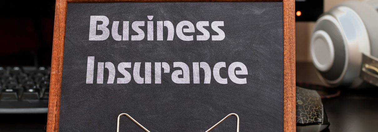 Business Insurance Services Concept. The text is written on a chalk board located at the workplace near the computer.